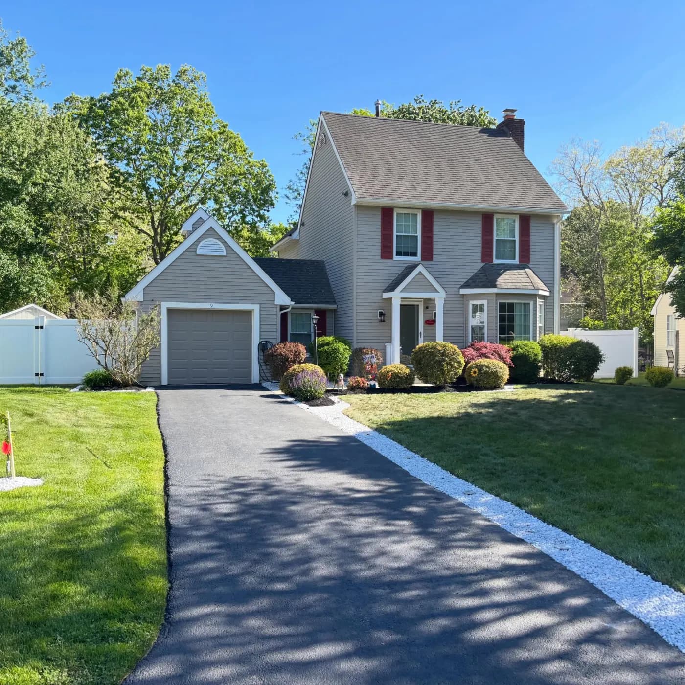 Freshly paved driveway with a clean white-stone border and trimmed front beds in South Jersey