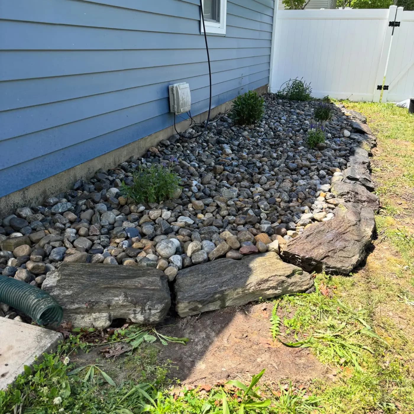River-rock drainage bed with flat-stone border along the side of a home in South Jersey