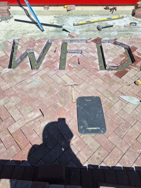 Custom herringbone paver patio with charcoal lettering inlay in Linwood, NJ