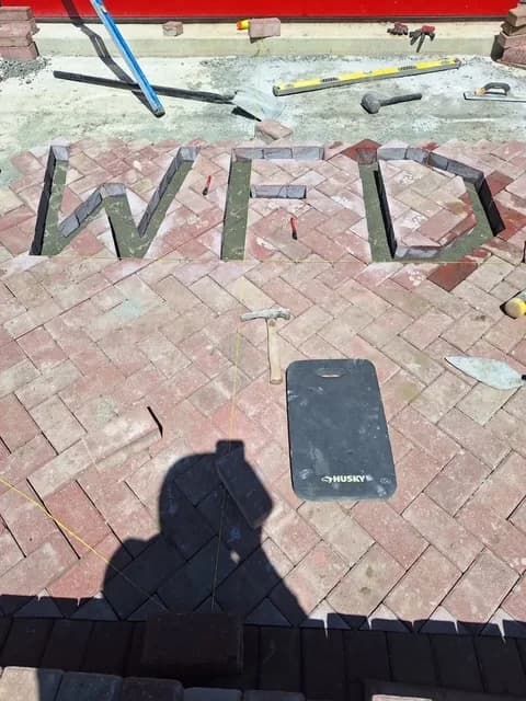 Custom herringbone paver patio with charcoal lettering inlay in Linwood, NJ
